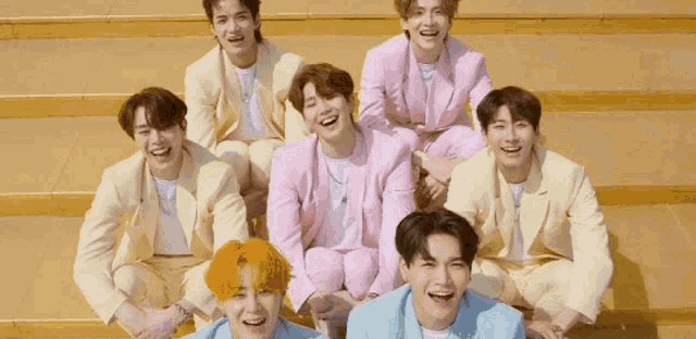 a group of young men are sitting on top of a set of stairs laughing .