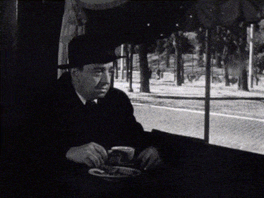 a man in a hat sits at a table with a plate of food on it