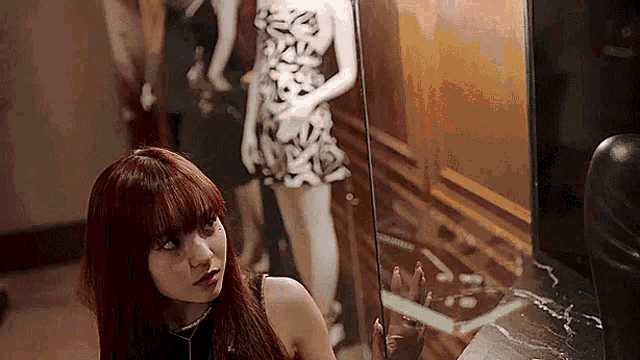 a woman is standing in front of a mirror looking at her reflection .