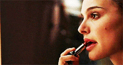 a woman is applying red lipstick to her lips in front of a mirror