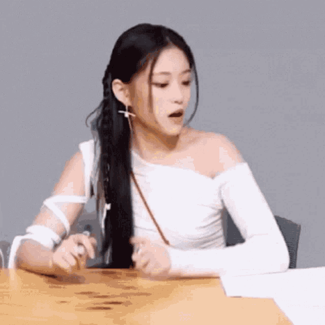 a woman is sitting at a table with a cast on her arm and a braid in her hair .