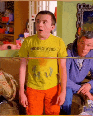 a boy wearing a yellow shirt that says ' slbs13 ' on it looks surprised