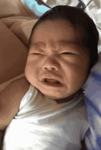 a baby with a white shirt on is crying