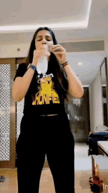 a woman wearing a t-shirt that says honified is holding a bottle of water .