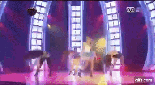 a group of people are dancing on a stage in front of a purple background .