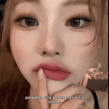 a close up of a woman 's face with the words parpadea si le perteneces a nia sheon below her