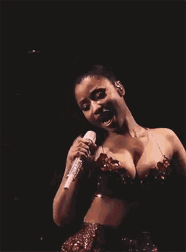 a woman is singing into a microphone on a stage .