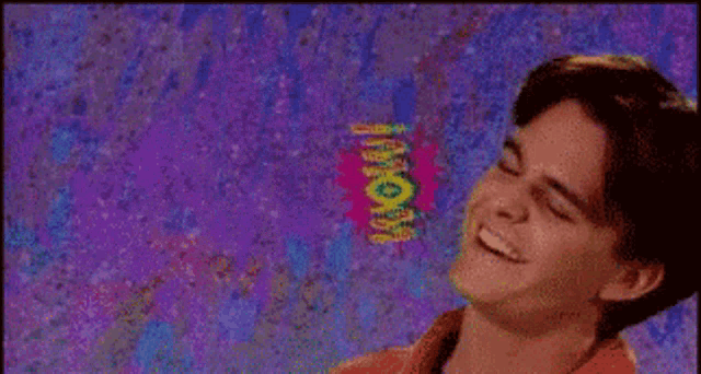 a man is smiling in front of a purple background with the word wow written on it