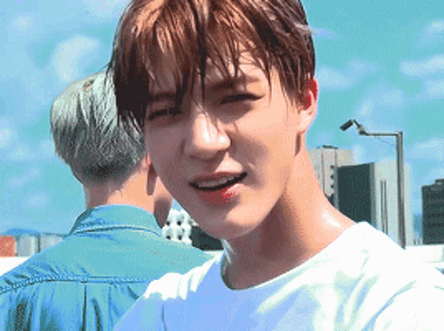 a close up of a young man 's face with a white shirt on