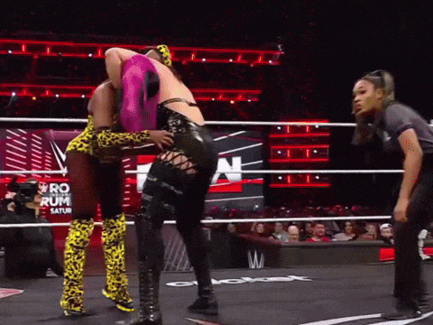 two women wrestling in a ring with the word saturn on the wall behind them