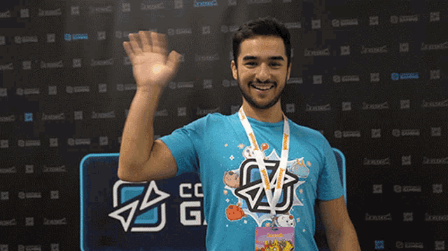 a man wearing a blue shirt with the letter g on it waves his hand