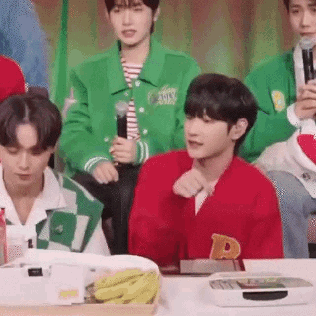 a group of young men are sitting at a table eating bananas .