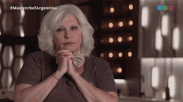 a woman with her hands folded in front of a masterchef argentina logo