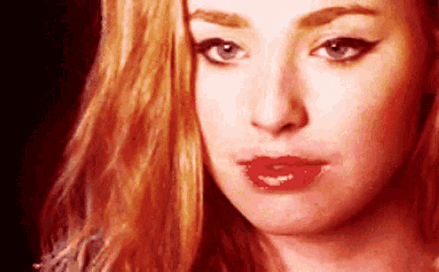 a close up of a woman 's face with red lipstick on her lips .