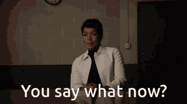 a woman says " you say what now " in front of a clock