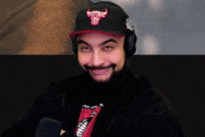 a man with a beard wearing a hat and headphones is smiling .