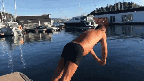 a man in black swim trunks is jumping into the water