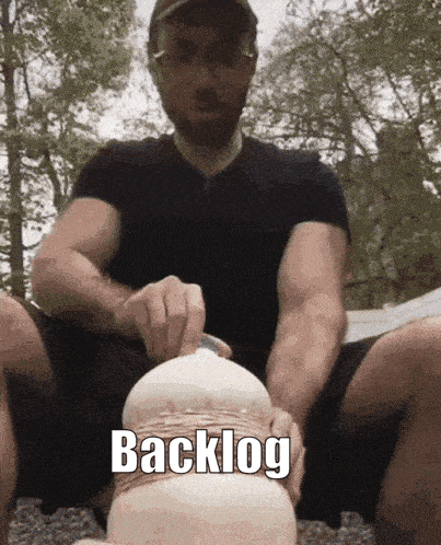 a man in a black shirt is holding a white object with the word backlog written on the bottom
