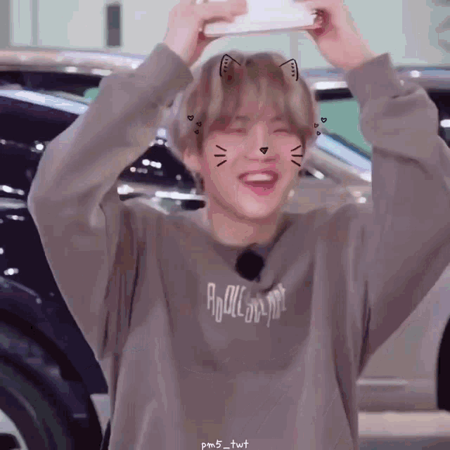 a person wearing a sweater with a cat face on it is holding a cell phone in their hand .