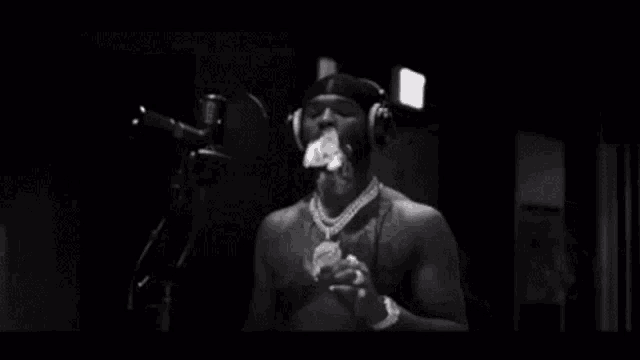 a man is smoking a cigarette in front of a microphone while wearing headphones .