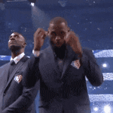 two men in suits are dancing on a stage in front of an american flag