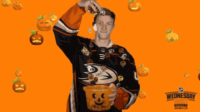 a hockey player is holding a trick or treat bucket in front of pumpkins
