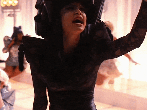 a woman in a black lace dress is holding her arms up in the air