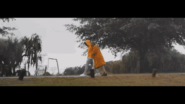 a person in a yellow raincoat is walking a dog in the rain