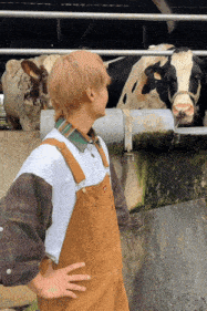 a man in overalls is standing in front of a cow