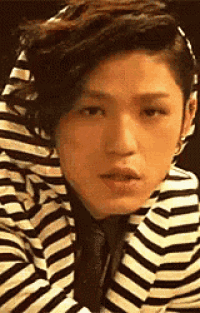 a man wearing a striped jacket and tie is making a funny face .