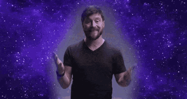 a man in a black shirt is standing in front of a purple background .