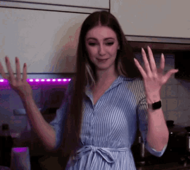 a woman wearing a blue and white striped shirt is waving her hands