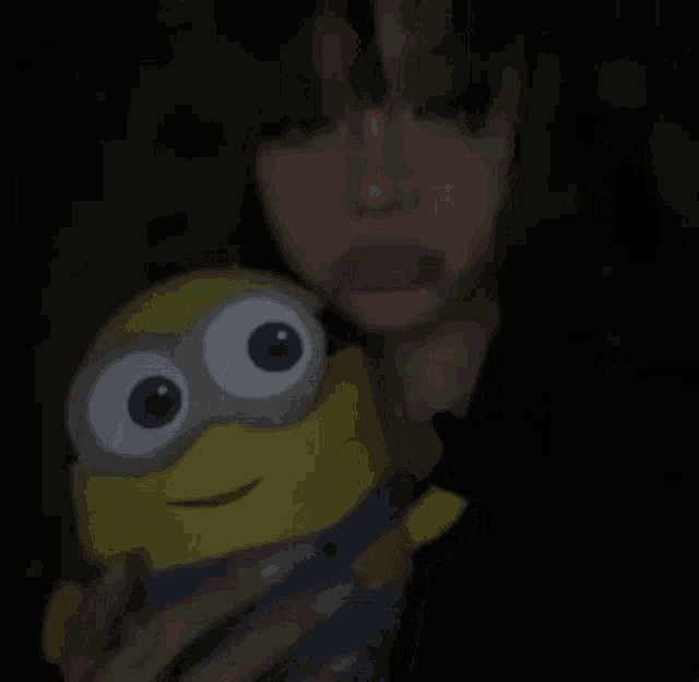 a girl is holding a stuffed minion in her arms .