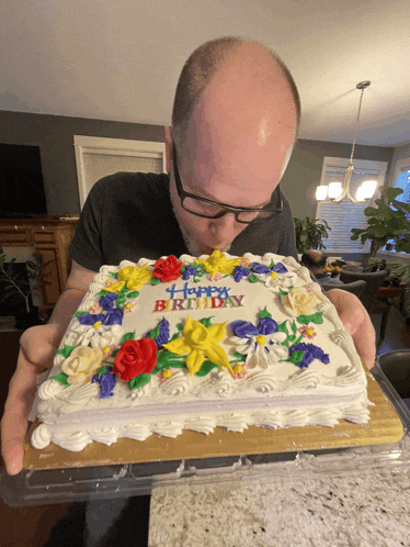 a man is blowing out a birthday cake that says happy birthday on it