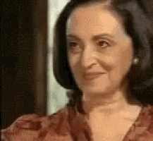 a woman is smiling and looking at the camera while wearing a red shirt .