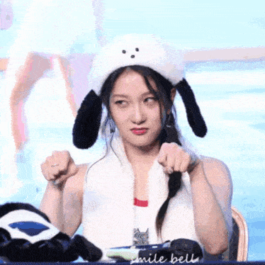a woman wearing a hat with ears and a scarf around her neck says smile bell