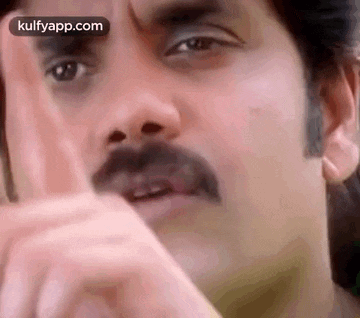 a man with a mustache is making a funny face with his hands .