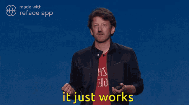 a man wearing a red shirt that says it 's two is giving a presentation