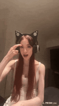 a woman with long red hair is wearing a cat ear headband and headphones .