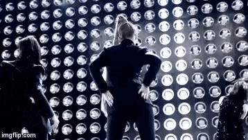 a group of people are standing in front of a wall of lights .