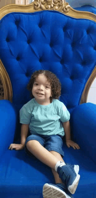 a little boy is sitting in a blue chair and smiling