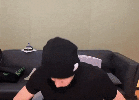 a man in a black hat is sitting on a couch .