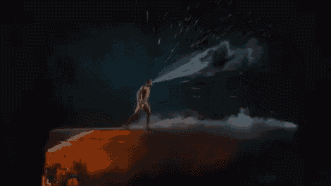 a man is standing on a cliff with a light coming out of his hand