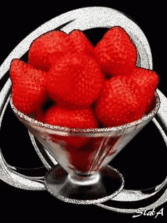 a martini glass filled with red strawberries with a black background