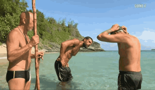 three men are standing in the water with giorno 17 written on the bottom of the screen