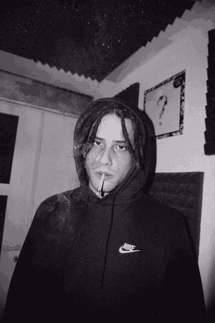 a man wearing a nike hoodie smoking a cigarette
