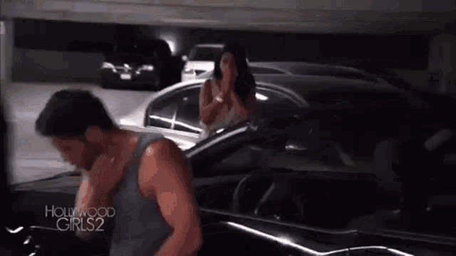 a man is talking on a cell phone next to a woman in a car in a parking garage .