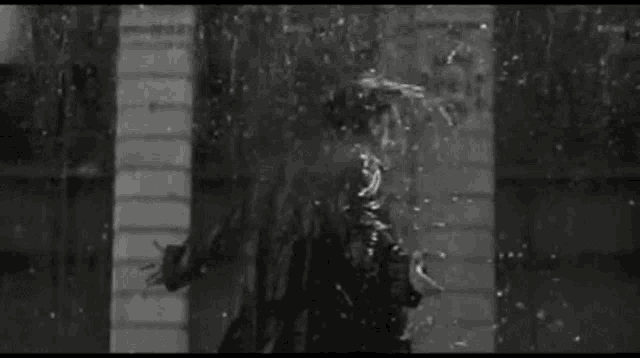 a man in a raincoat is standing in the rain .