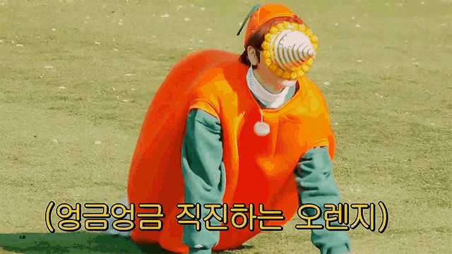 a person dressed in an orange costume with korean writing on the bottom
