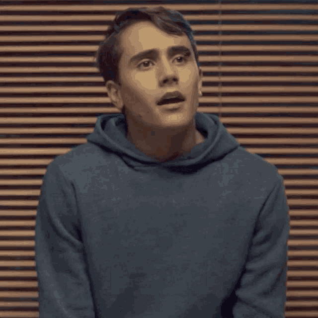 a young man in a blue hoodie is making a funny face .